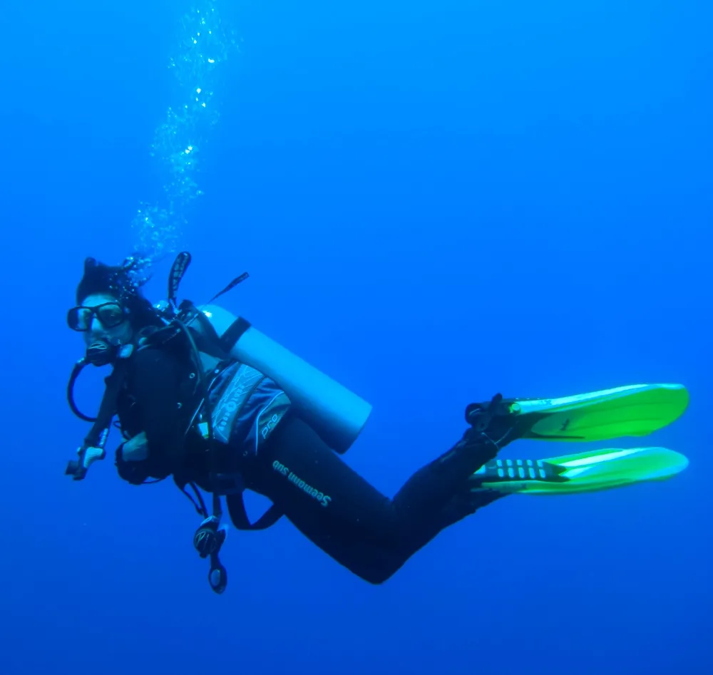 Die Autorin als Taucherin im tiefblauen Wasser, über ihr steigen Luftblasen auf